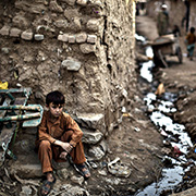 A child sitting outside a simple home