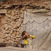 A young child outside a simple home